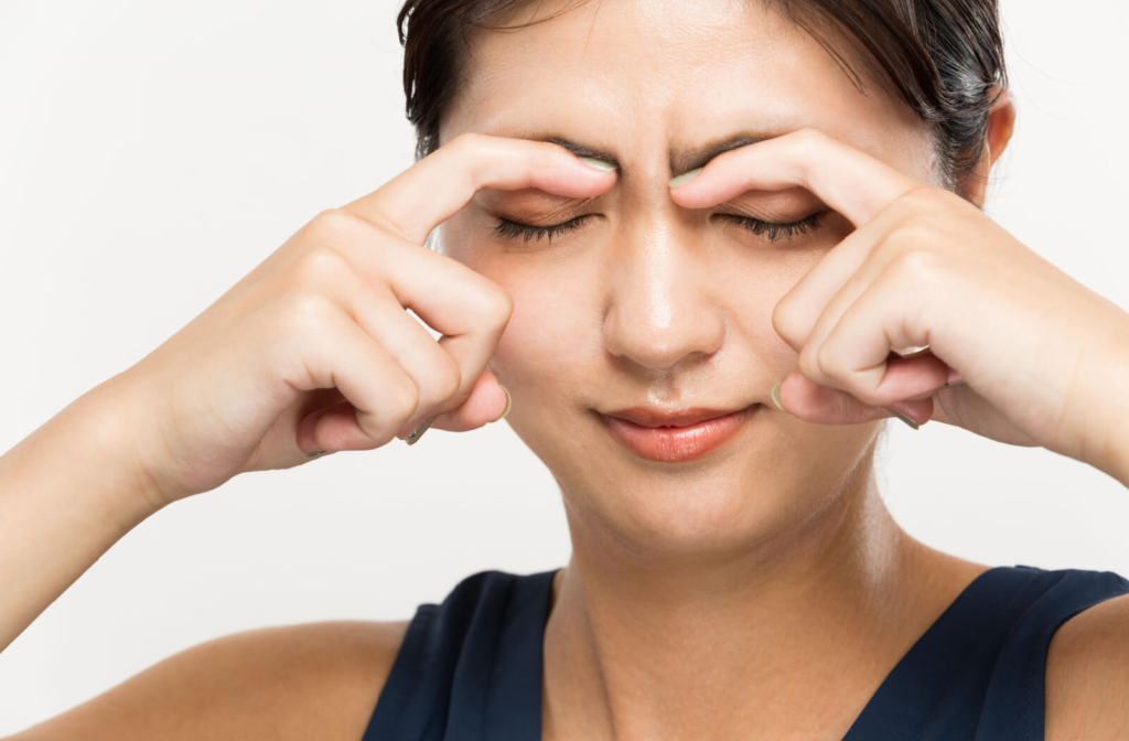 A woman is massaging her eyelids to relax the muscles from twitching.