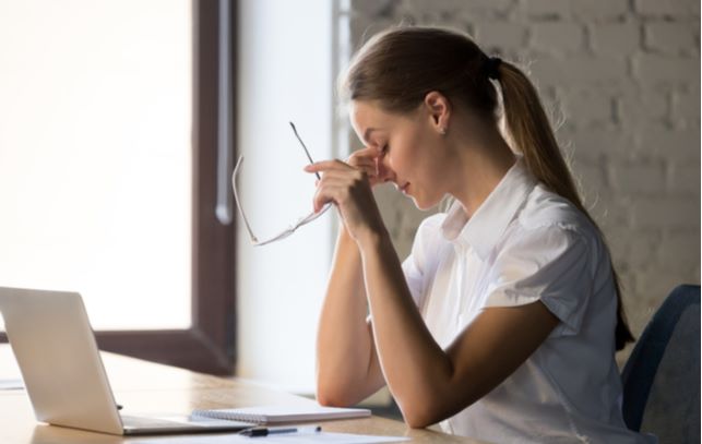 Women experiencing dry eye while using laptop at workplace