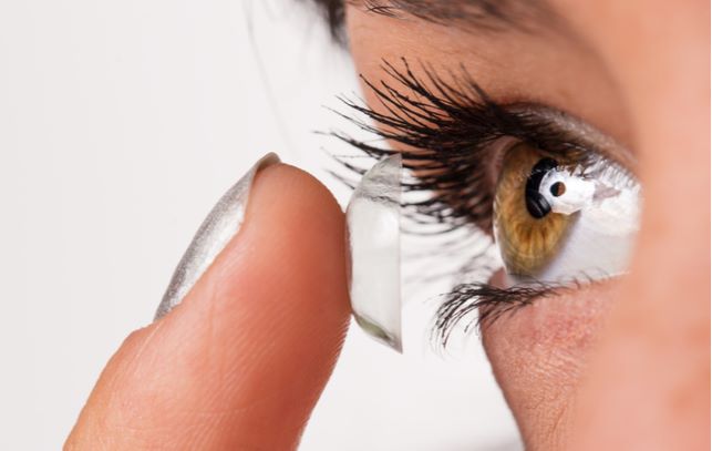 Close up of women putting in contact lenses into eye