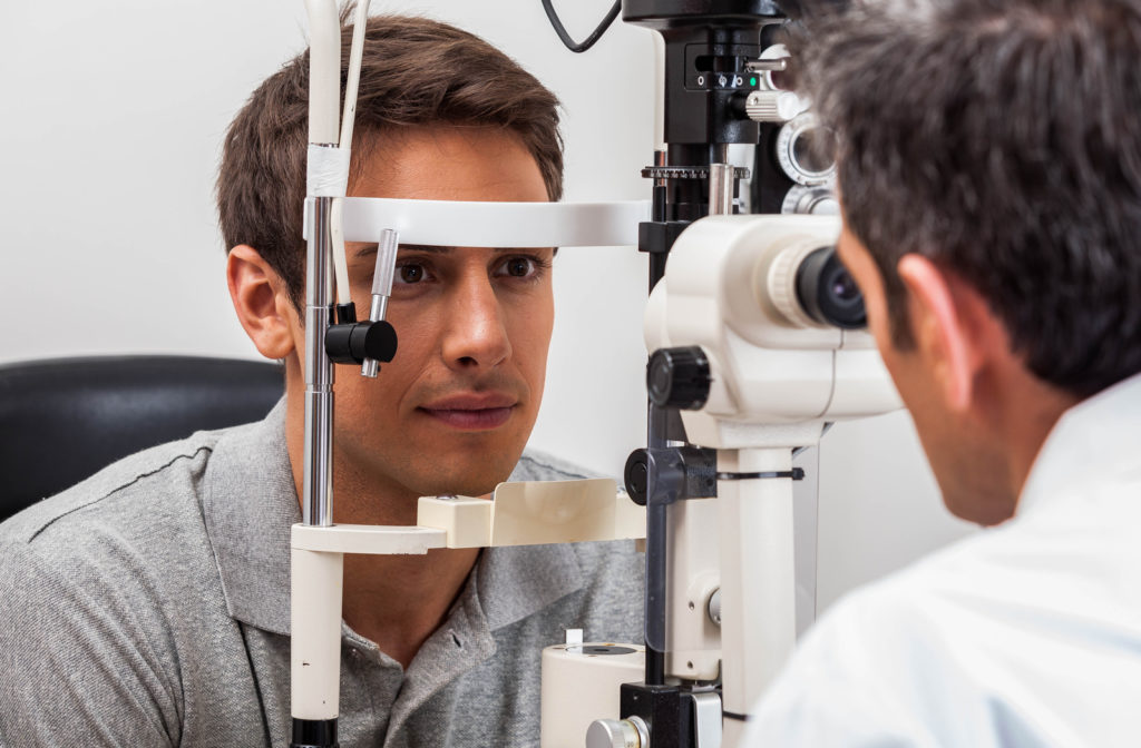 Man at optometrist office getting eye exam by placing chin on machine
