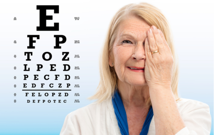 Older women covering up one eye to undergo eye exam with eye exam chart in the background