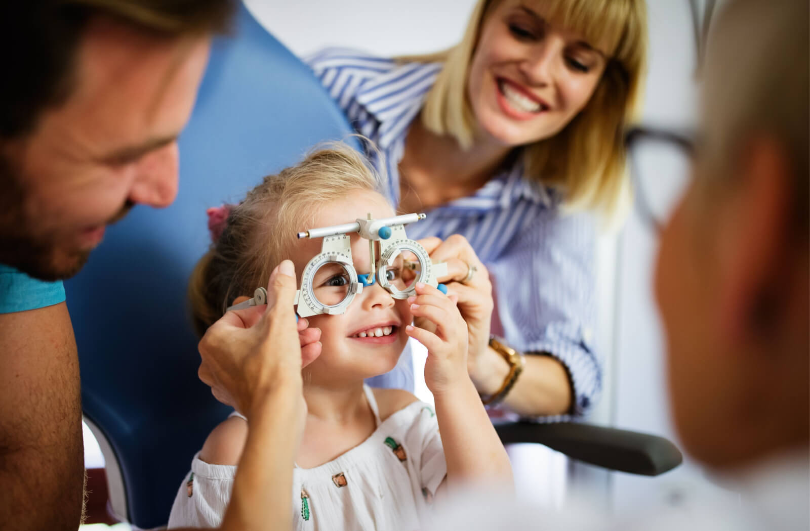 An optician is checking a female child's vision with possible myopia.