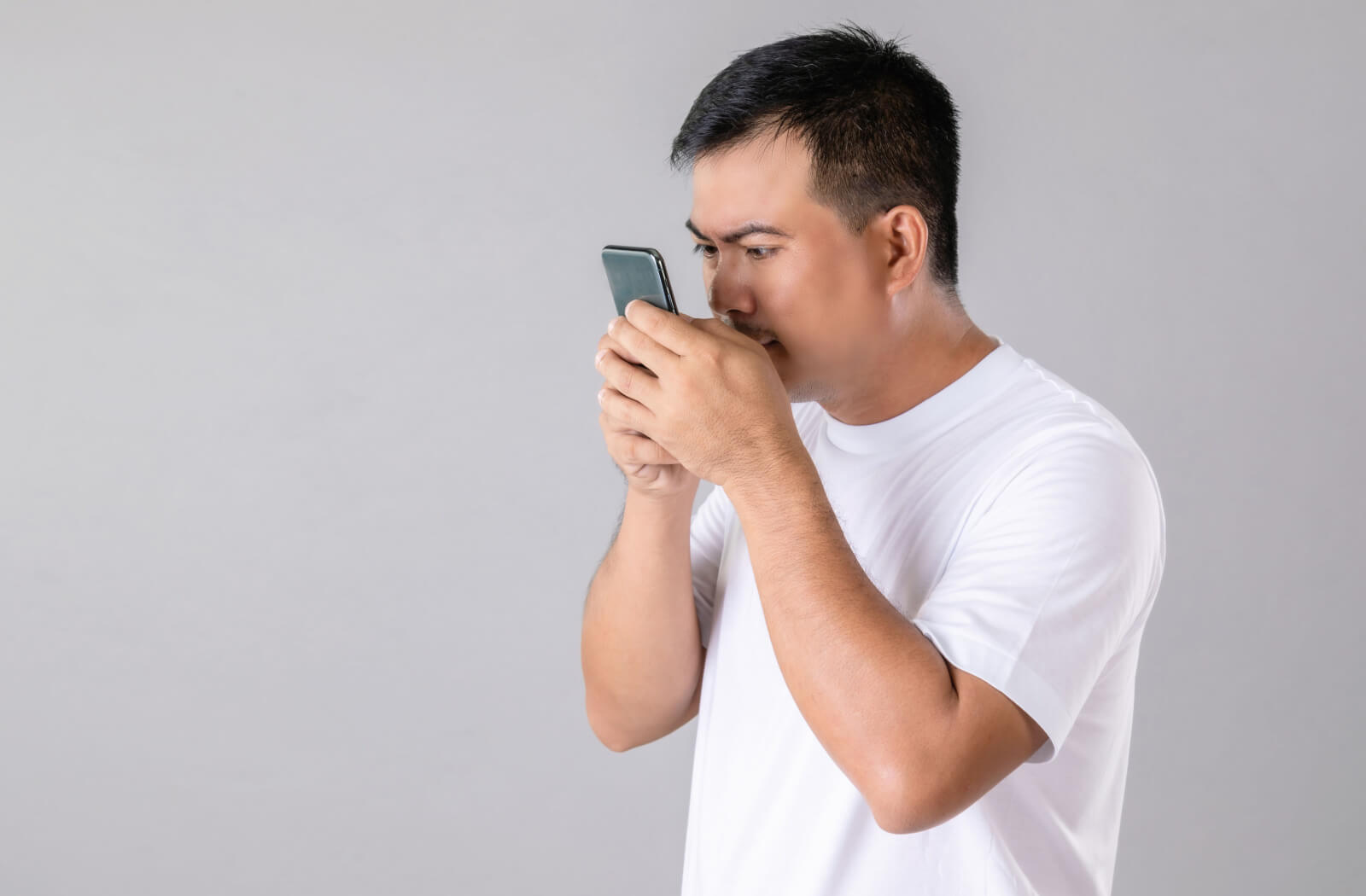 A man using smartphone is holding his mobile phone too close on his eyes.