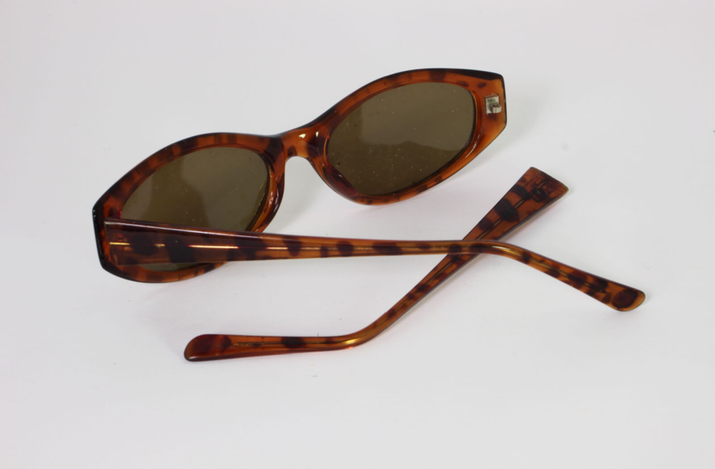 a pair of brown sunglasses with one arm broken off at the hinge