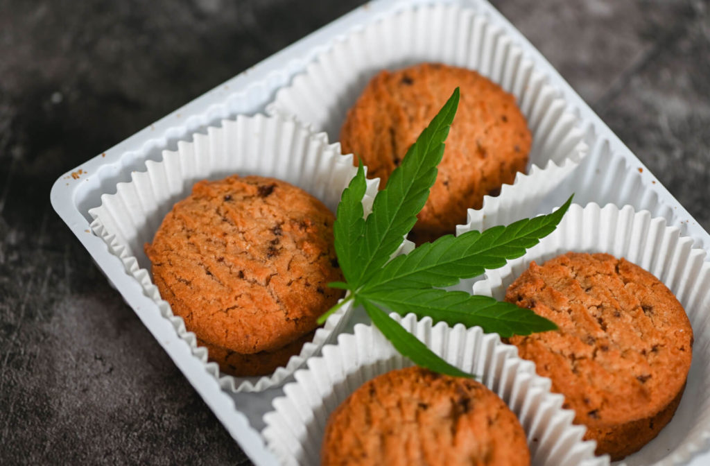 "Chocolate chip cookies in a square box with a cannabis leaf placed on top."
