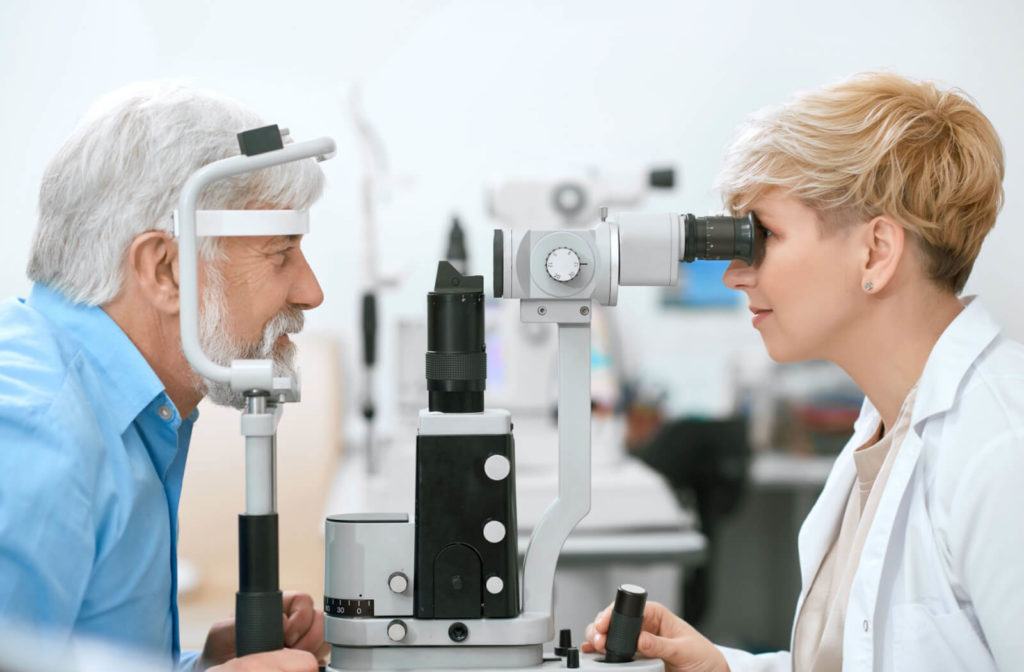 A female optometrist looking into a medical device to perform an eye exam on a senior man