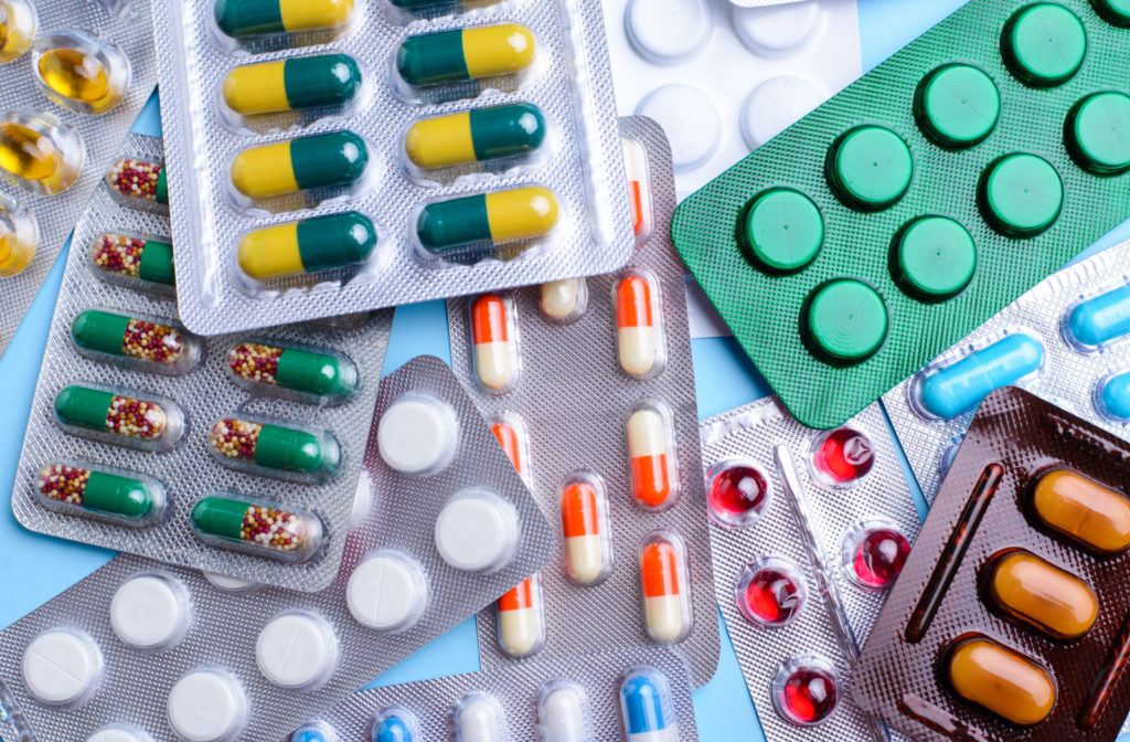 An assortment of differently colored medications against a blue background.