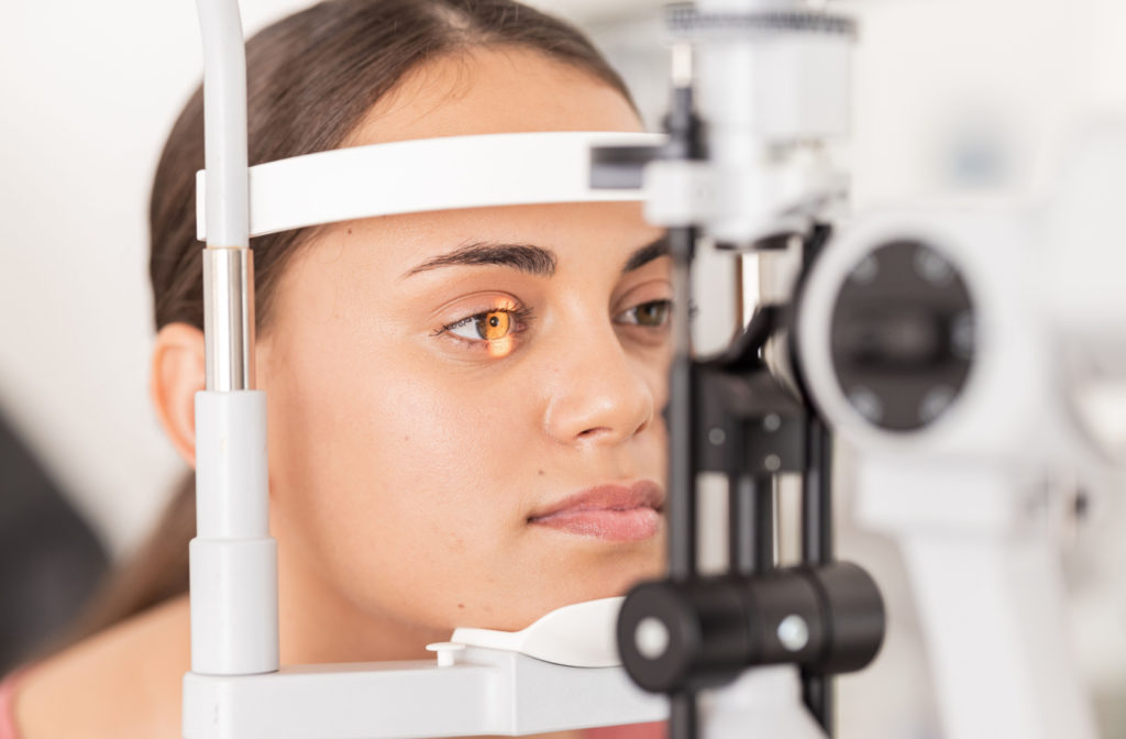 A young woman with brown eyes sitting down for a slit-lamp examination.